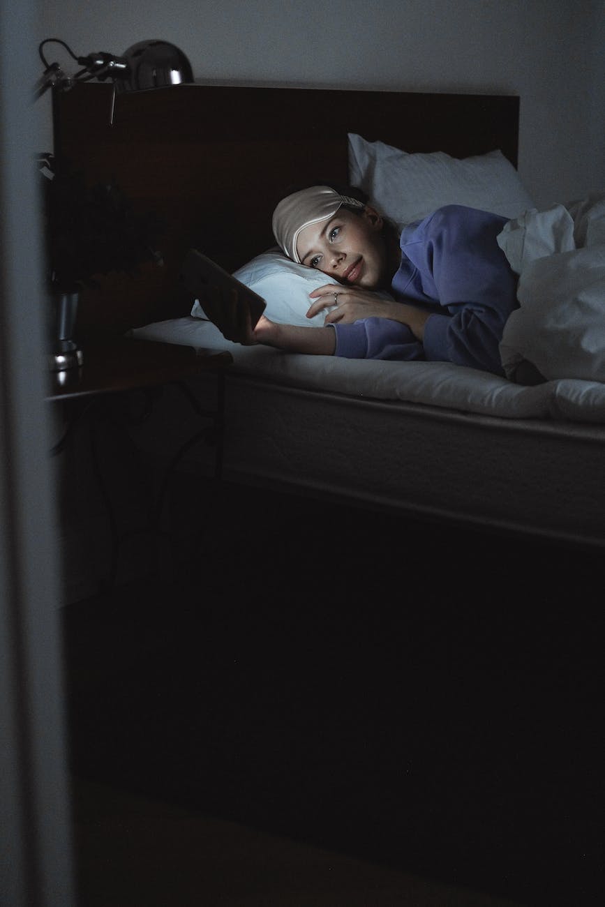 woman lying on bed while using a cellphone
