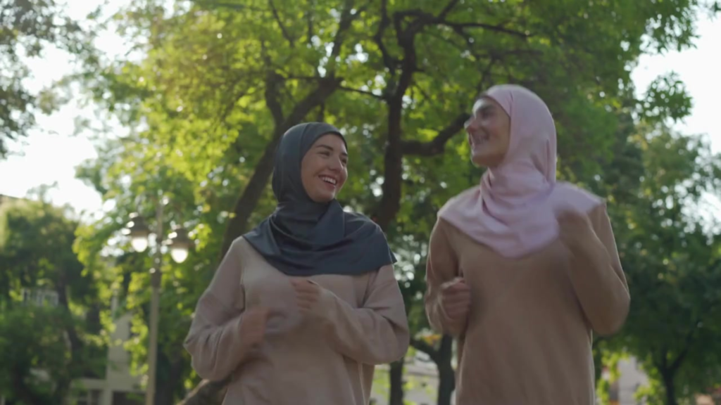 Two energetic Muslim women jogging together, depicting renewed energy, focus, and barakah after realigning with natural cycles.